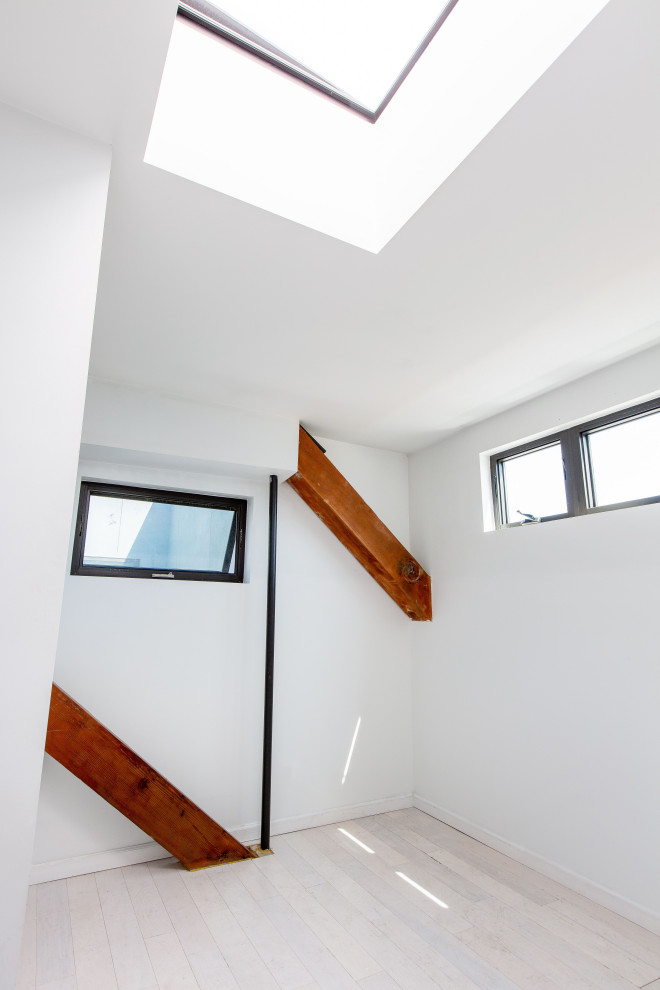 Modelo de dormitorio contemporáneo con paredes blancas, suelo de madera clara y suelo beige