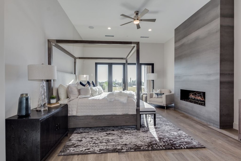 Ejemplo de dormitorio principal minimalista extra grande con chimenea lineal, marco de chimenea de hormigón, paredes blancas, suelo de madera clara y suelo gris