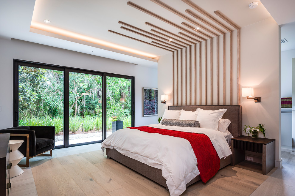 Diseño de dormitorio principal actual sin chimenea con paredes blancas, suelo de madera clara y suelo marrón