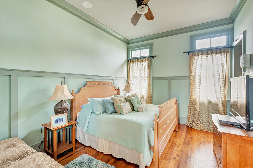 Foto di una camera da letto tropicale con pareti verdi e pavimento in legno massello medio