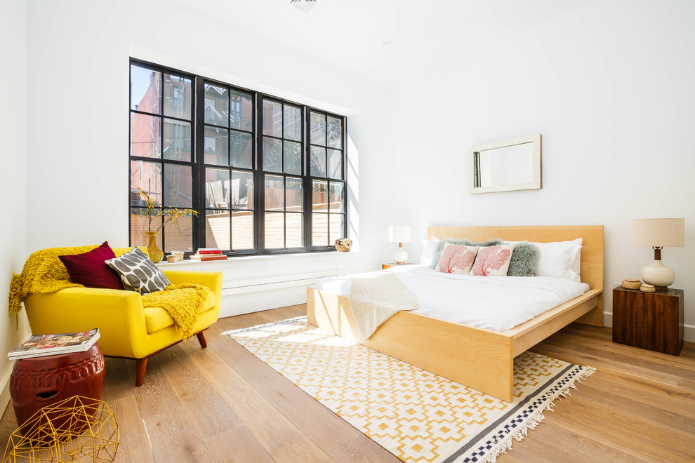Trendy light wood floor and brown floor bedroom photo in New York with white walls
