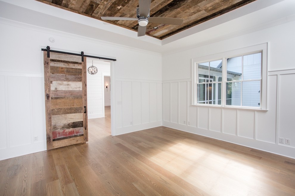 Imagen de dormitorio de estilo de casa de campo grande sin chimenea con paredes blancas, suelo de madera en tonos medios y suelo marrón