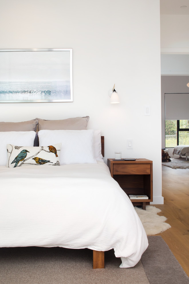 This is an example of a contemporary bedroom in San Francisco with white walls and light hardwood flooring.