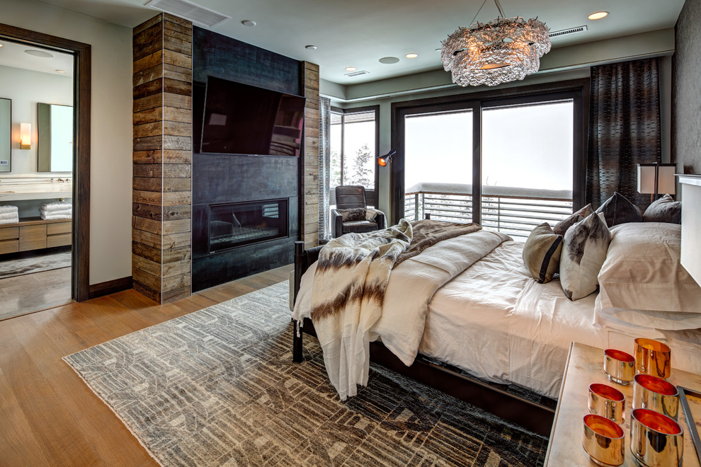 This is an example of a large contemporary master bedroom in Salt Lake City with beige walls, light hardwood flooring, a standard fireplace, a plastered fireplace surround and beige floors.