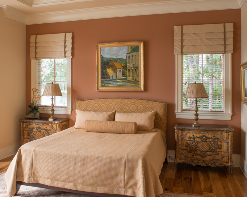 Cette image montre une grande chambre parentale design avec un mur orange, un sol en bois brun et aucune cheminée.