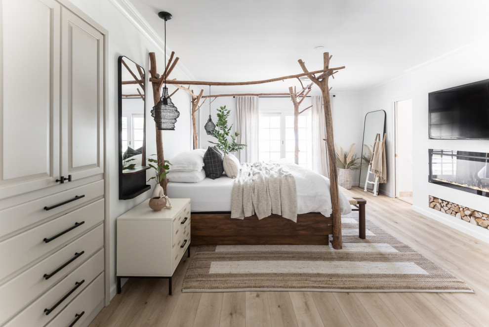 Idée de décoration pour une chambre parentale bohème de taille moyenne avec un mur blanc, parquet clair, une cheminée ribbon et un manteau de cheminée en plâtre.