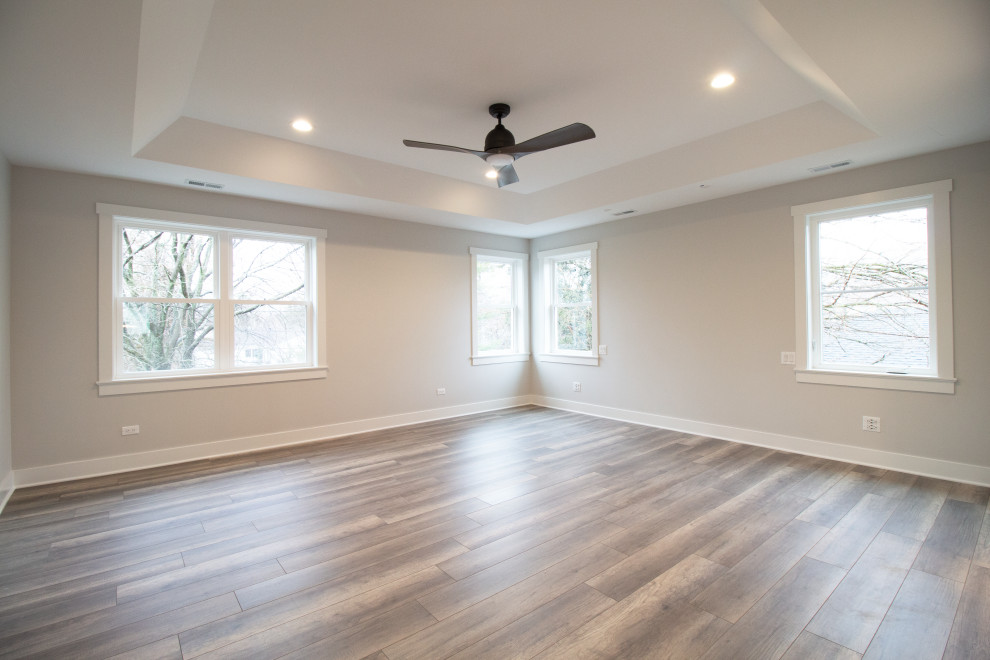 Cette image montre une grande chambre parentale design avec un mur beige, un sol en bois brun, un sol marron et un plafond à caissons.