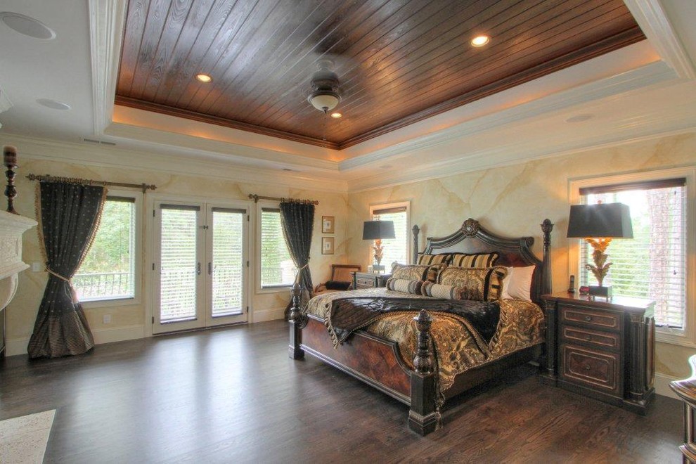 Foto de dormitorio principal clásico grande con suelo de madera oscura, todas las chimeneas y marco de chimenea de piedra