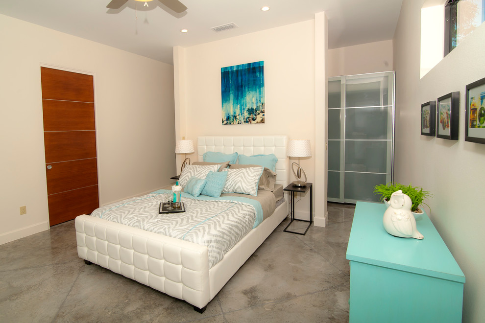 Imagen de dormitorio principal contemporáneo de tamaño medio sin chimenea con paredes blancas y suelo de cemento
