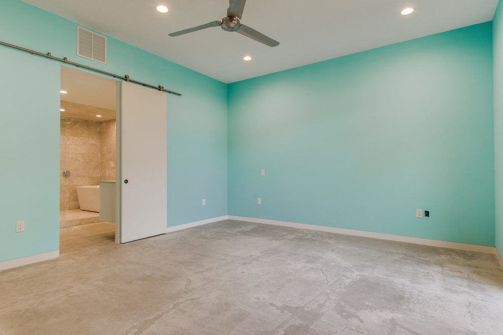 Modernes Hauptschlafzimmer ohne Kamin mit blauer Wandfarbe und Betonboden in Dallas