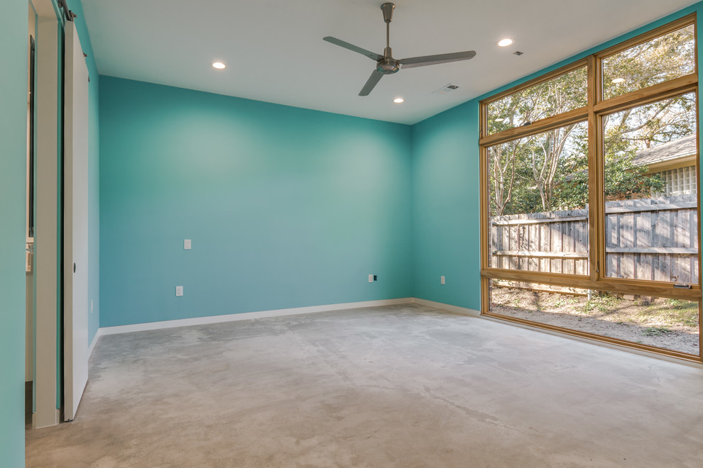 Modernes Hauptschlafzimmer ohne Kamin mit blauer Wandfarbe und Betonboden in Dallas