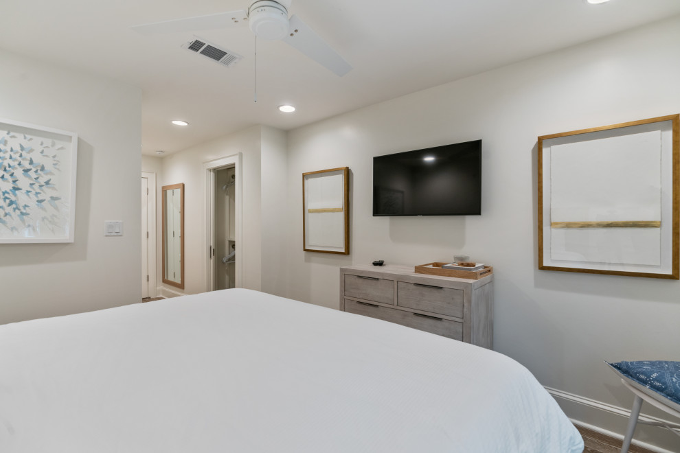 Mittelgroßes Maritimes Schlafzimmer mit weißer Wandfarbe, braunem Holzboden, Tunnelkamin, verputzter Kaminumrandung und grauem Boden in Sonstige