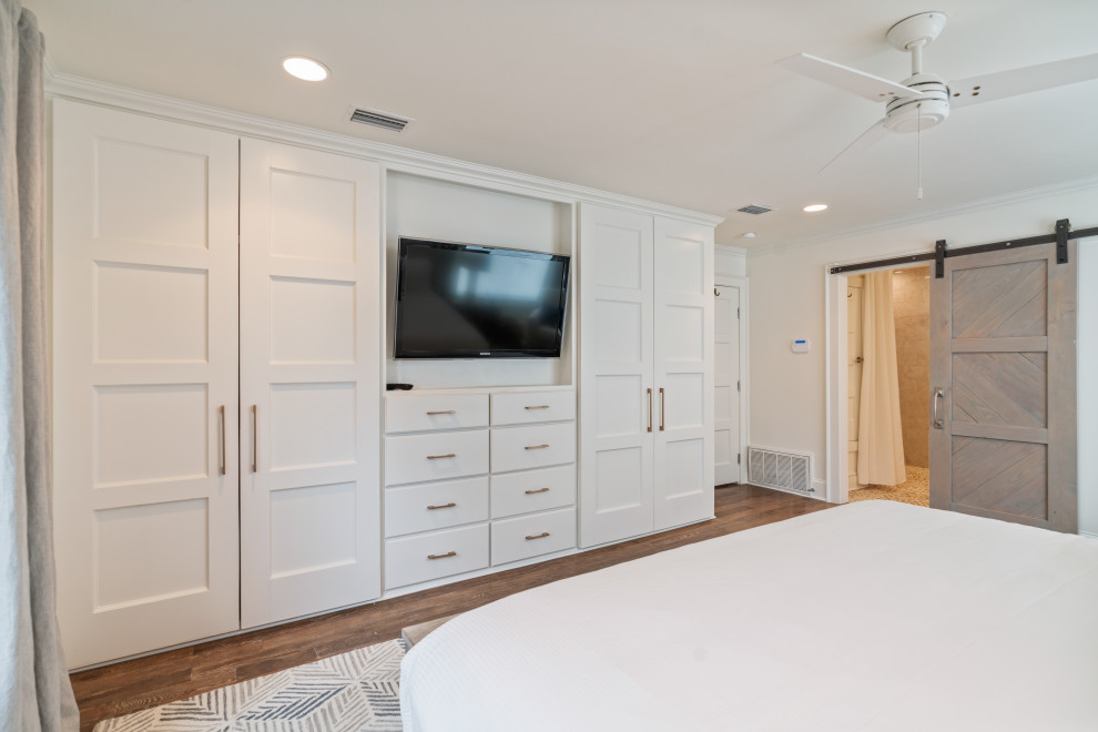 Diseño de dormitorio marinero de tamaño medio con paredes blancas, suelo de madera en tonos medios, chimenea de doble cara, marco de chimenea de yeso y suelo gris