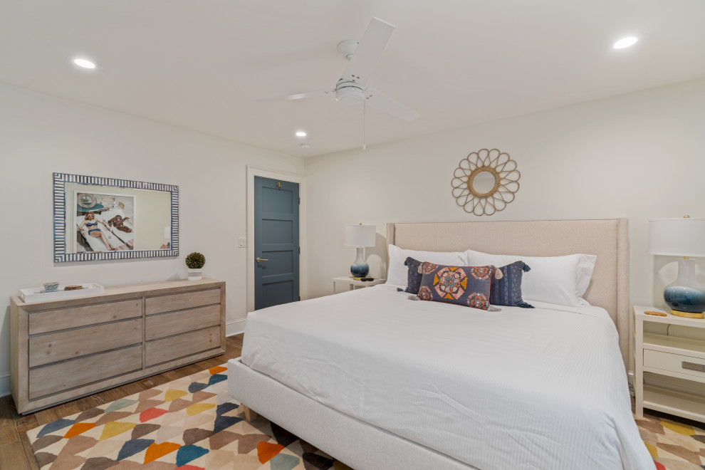 Пример оригинального дизайна: спальня среднего размера в морском стиле с белыми стенами, паркетным полом среднего тона, двусторонним камином, фасадом камина из штукатурки и серым полом