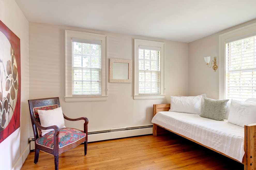 Idée de décoration pour une chambre d'amis tradition de taille moyenne avec un mur blanc et un sol en bois brun.