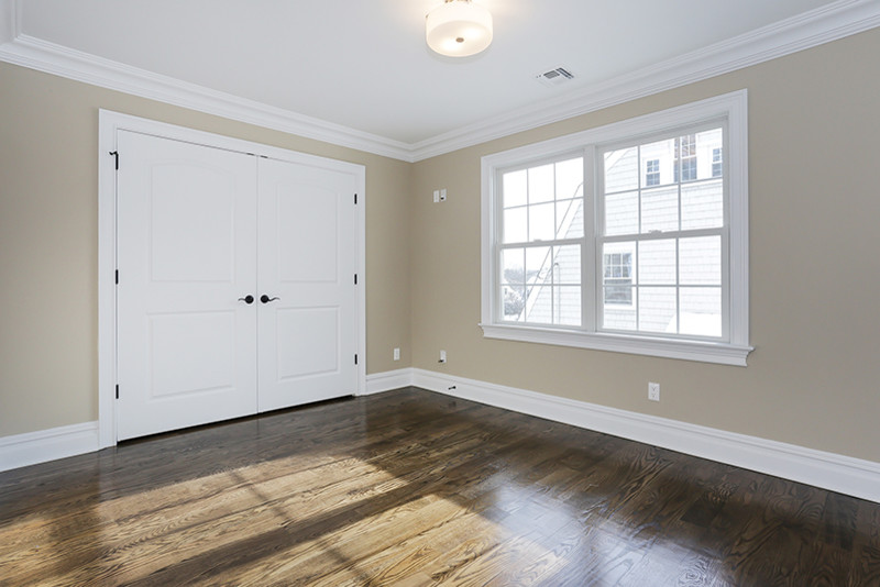 Imagen de habitación de invitados moderna grande con paredes beige y suelo de madera oscura