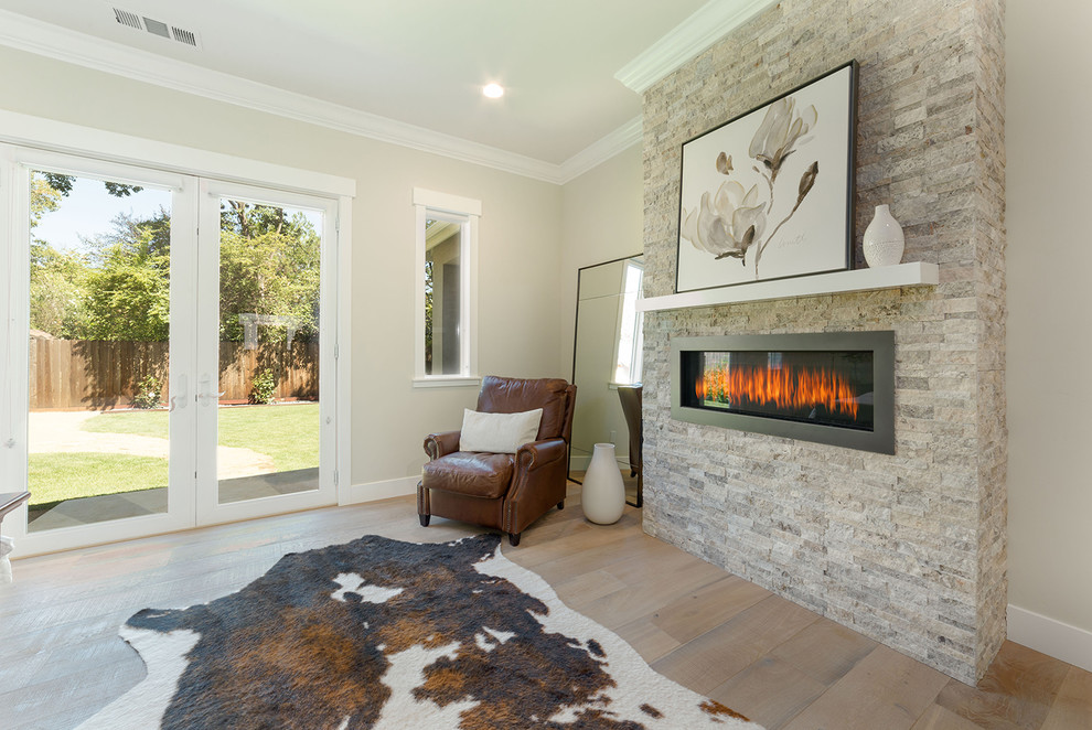 Mid-sized trendy master light wood floor and beige floor bedroom photo in Sacramento with beige walls, a standard fireplace and a stone fireplace