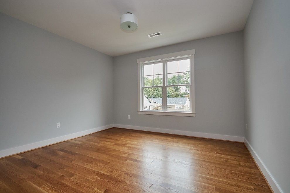 Example of a mid-sized farmhouse medium tone wood floor and brown floor bedroom design in DC Metro with gray walls and no fireplace