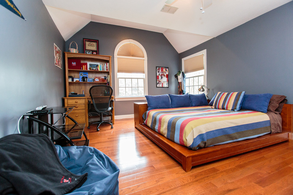 Cette photo montre une grande chambre d'amis chic avec un mur bleu et un sol en bois brun.