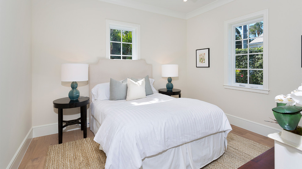 Imagen de habitación de invitados tropical de tamaño medio sin chimenea con paredes beige, suelo de madera clara y suelo beige