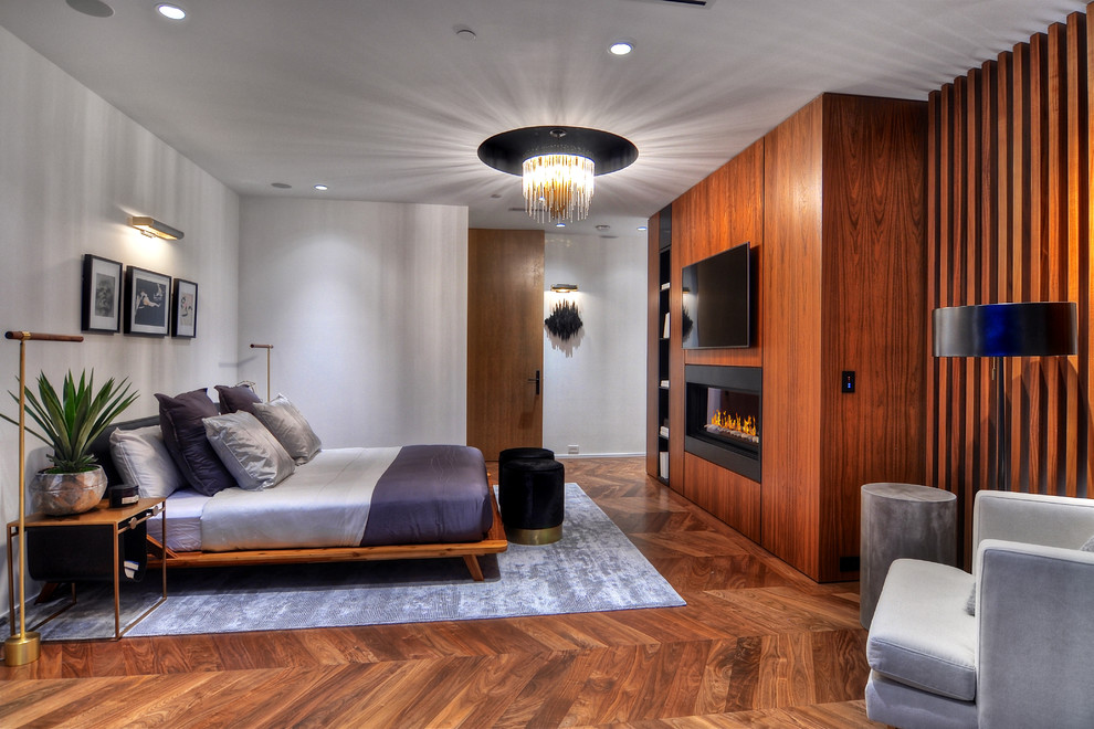 Großes Modernes Hauptschlafzimmer mit Hängekamin, weißer Wandfarbe, braunem Holzboden und braunem Boden in Orange County