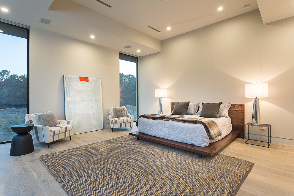 This is an example of a contemporary bedroom in Austin with white walls and light hardwood flooring.