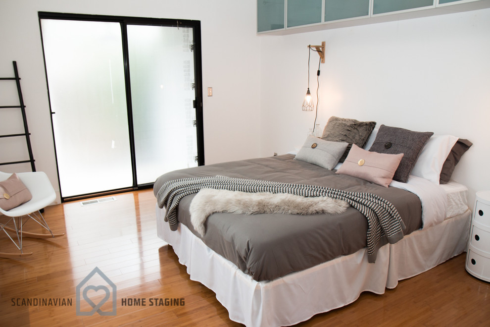 Ejemplo de dormitorio nórdico con paredes blancas y suelo de madera en tonos medios