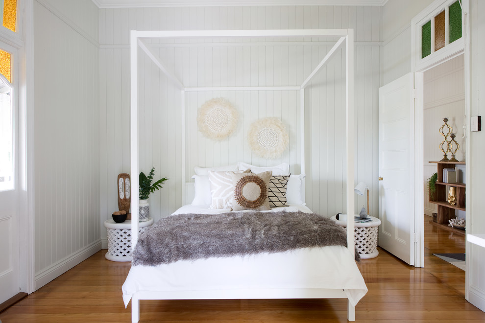 Foto på ett mellanstort lantligt sovrum, med vita väggar och mellanmörkt trägolv