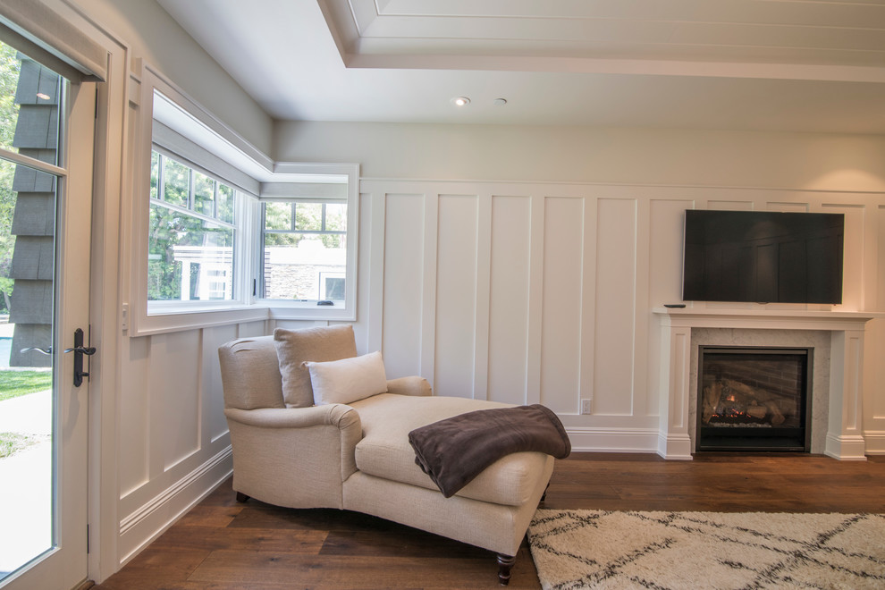 Cette photo montre une grande chambre parentale chic avec un mur blanc, un sol en bois brun, une cheminée standard et un manteau de cheminée en bois.