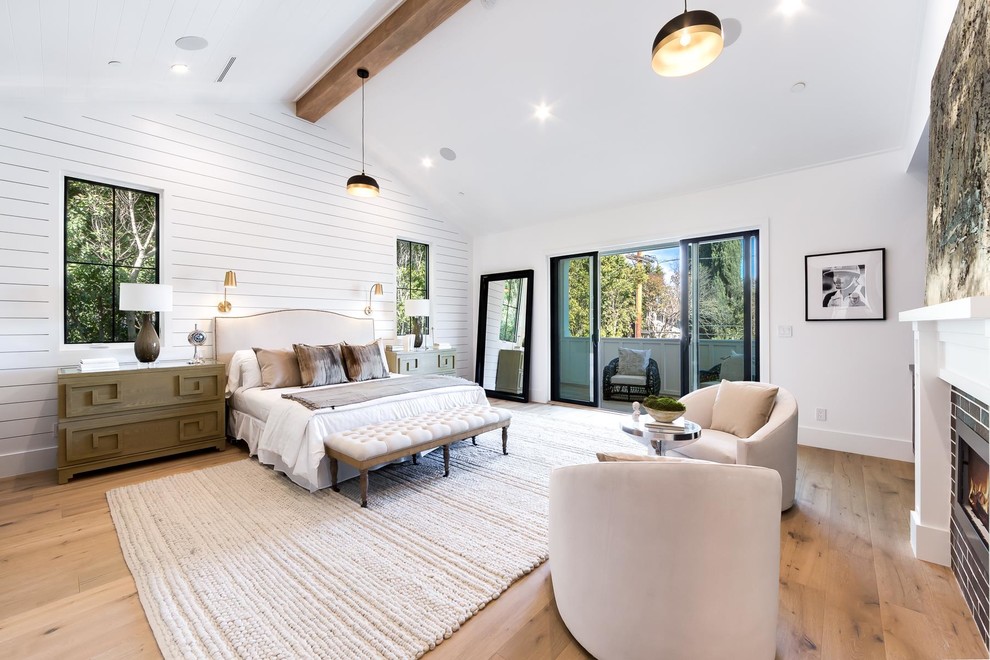 Landhausstil Schlafzimmer mit weißer Wandfarbe, braunem Holzboden, Gaskamin, gefliester Kaminumrandung und braunem Boden in Los Angeles
