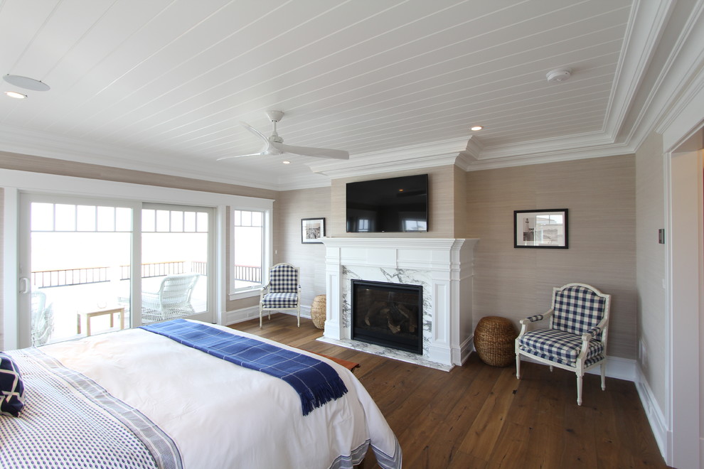 Großes Maritimes Hauptschlafzimmer mit beiger Wandfarbe, braunem Holzboden, Kamin, Kaminumrandung aus Stein und braunem Boden in Philadelphia