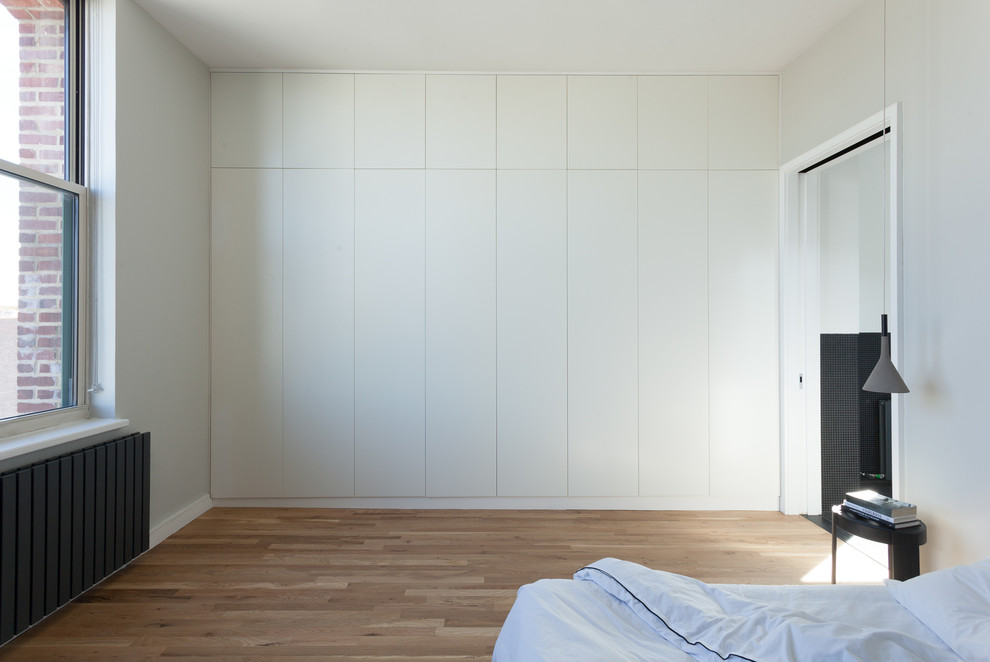 Cette photo montre une chambre parentale moderne de taille moyenne avec un mur blanc, parquet clair et aucune cheminée.