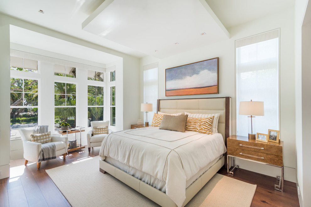 This is an example of a beach style master bedroom in Miami with white walls, medium hardwood flooring and no fireplace.