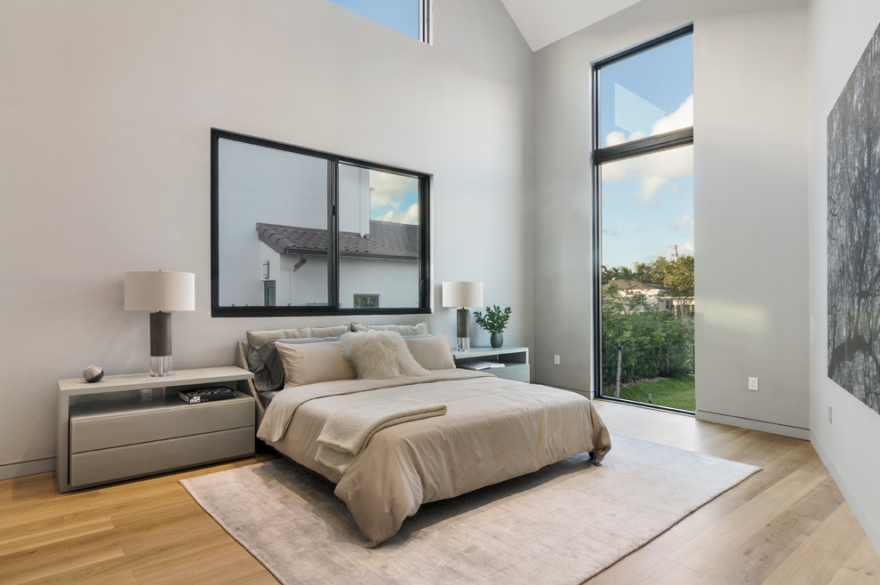 Modernes Schlafzimmer mit grauer Wandfarbe, hellem Holzboden und beigem Boden in Miami