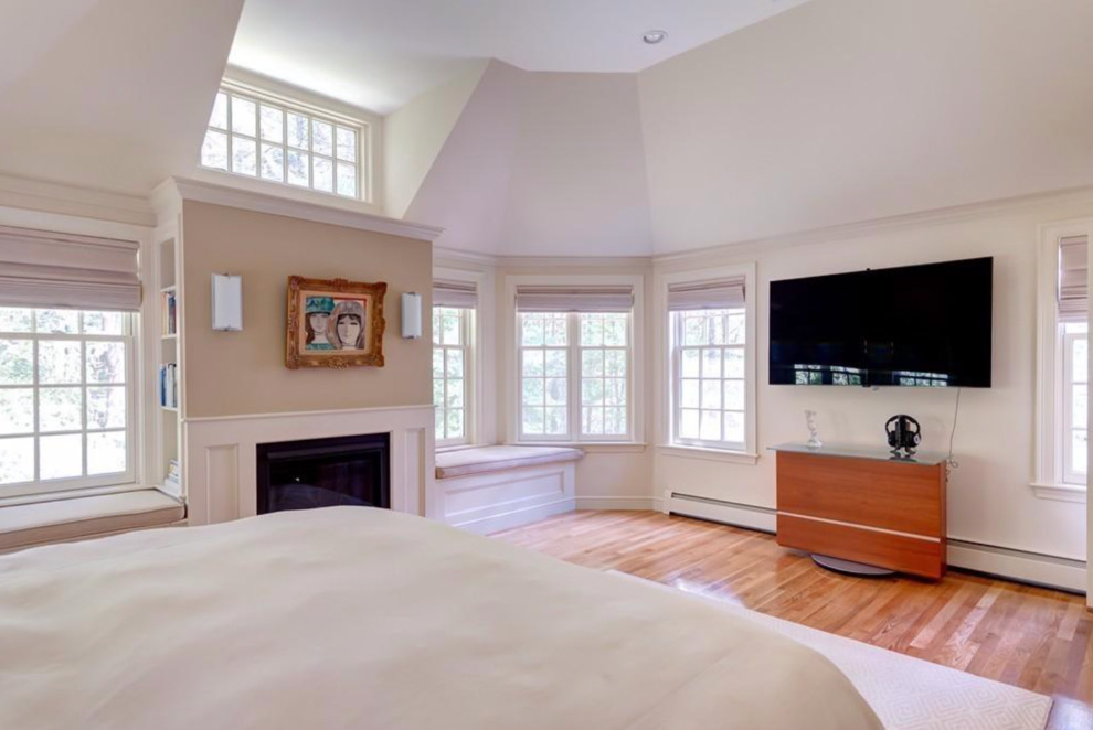 Inspiration for a large traditional master bedroom in Boston with beige walls, medium hardwood flooring, a standard fireplace and a wooden fireplace surround.