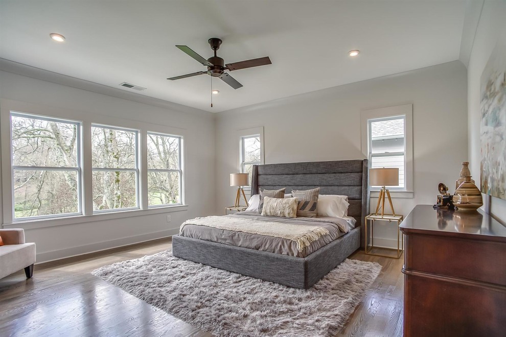 Modelo de dormitorio clásico renovado con paredes blancas, suelo de madera en tonos medios y suelo marrón
