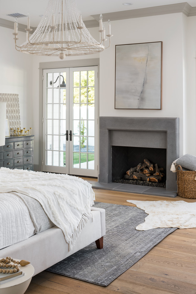 フェニックスにある広いカントリー風のおしゃれな主寝室 (白い壁、淡色無垢フローリング、標準型暖炉、コンクリートの暖炉まわり、茶色い床、グレーとブラウン)