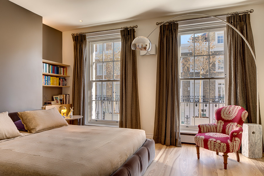Photo of a contemporary bedroom in London with beige walls and light hardwood flooring.