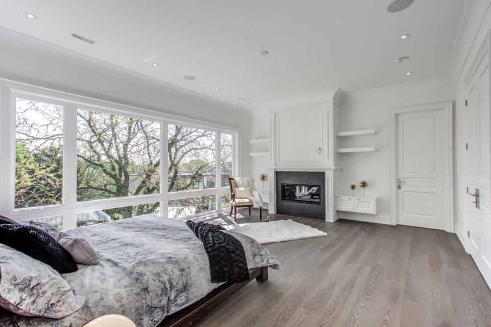 Design ideas for an expansive contemporary master bedroom in Toronto with white walls, medium hardwood flooring, a standard fireplace, a plastered fireplace surround and grey floors.