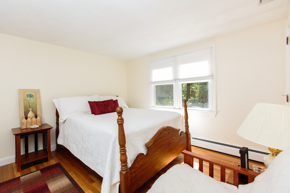 This is an example of a medium sized classic guest bedroom in Boston with white walls and medium hardwood flooring.