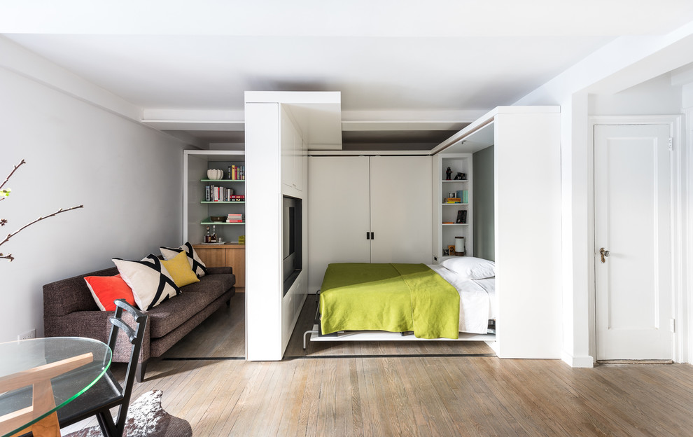 Modelo de dormitorio contemporáneo pequeño con paredes blancas y suelo de madera en tonos medios