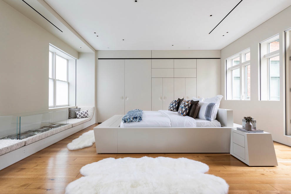 Example of a trendy medium tone wood floor and brown floor bedroom design in New York with white walls