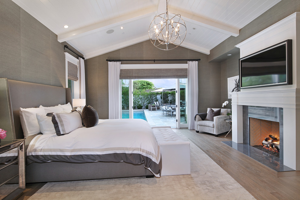 Klassisches Schlafzimmer mit grauer Wandfarbe, braunem Holzboden und Kamin in Orange County