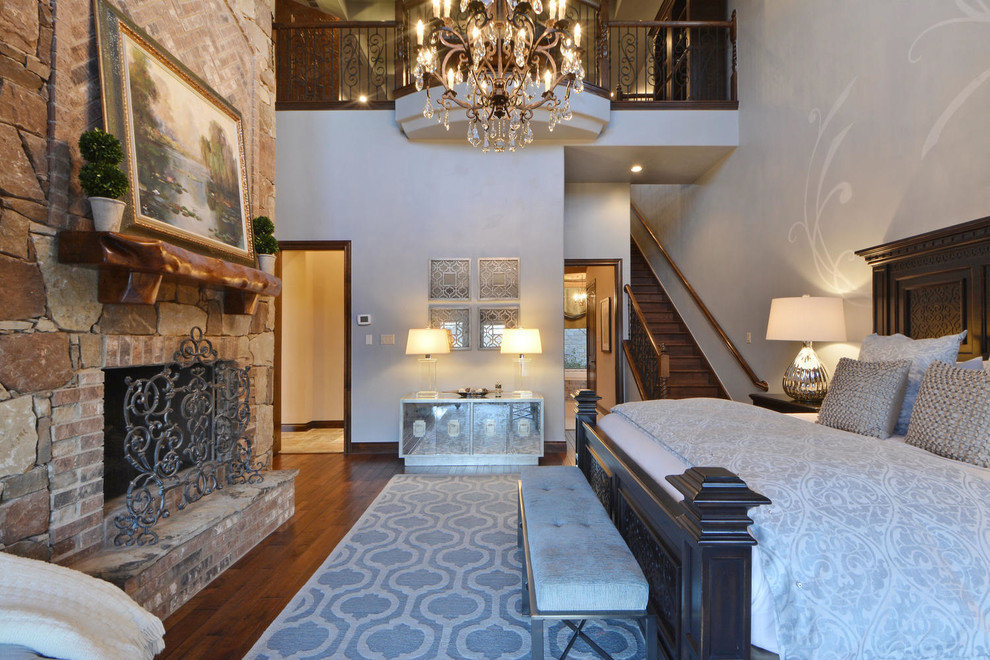 Example of a huge tuscan master dark wood floor bedroom design in Austin with gray walls, a standard fireplace and a stone fireplace
