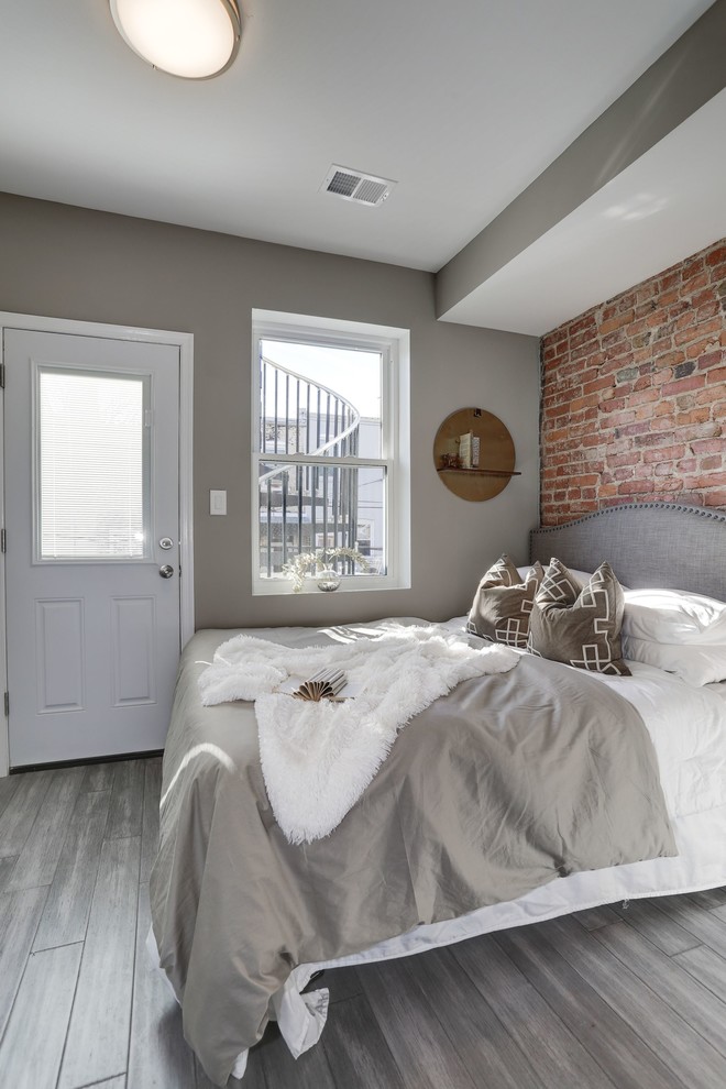 Photo of a small industrial bedroom in DC Metro with grey walls, light hardwood flooring and grey floors.