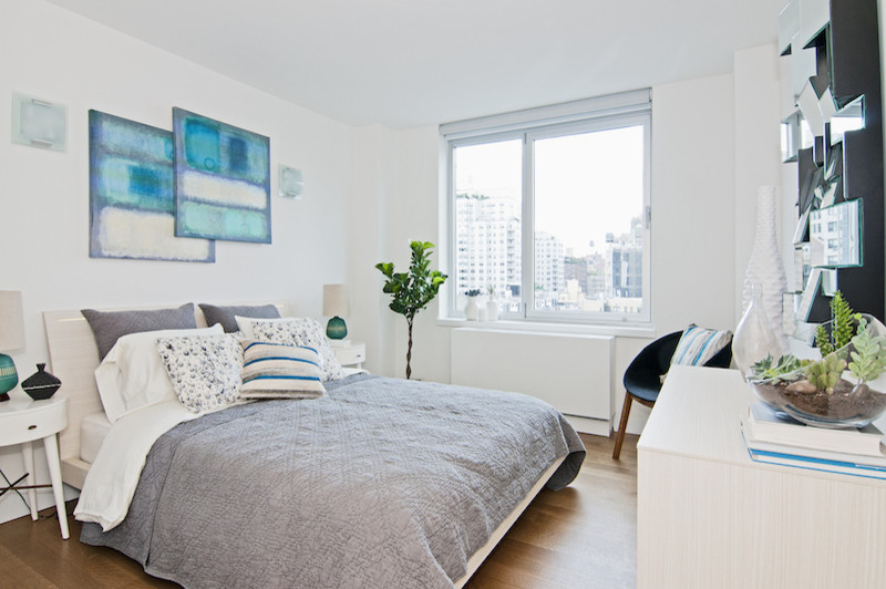 Mittelgroßes Modernes Hauptschlafzimmer ohne Kamin mit weißer Wandfarbe, braunem Holzboden und braunem Boden in New York