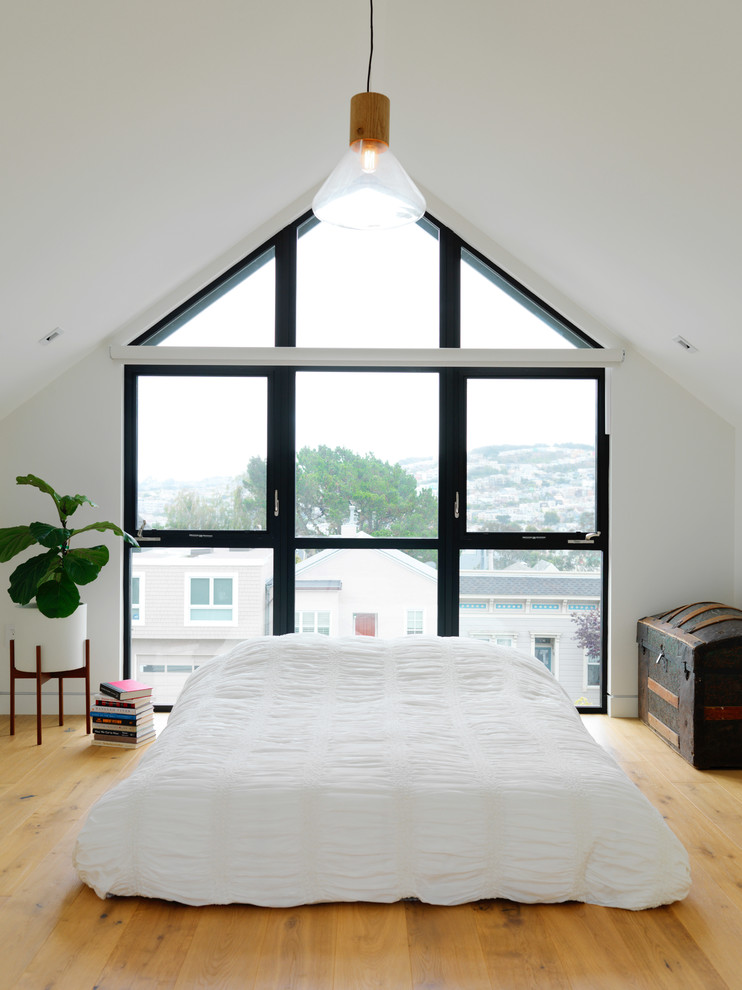 Cette photo montre une chambre tendance de taille moyenne avec un mur blanc, parquet clair, aucune cheminée et un sol marron.