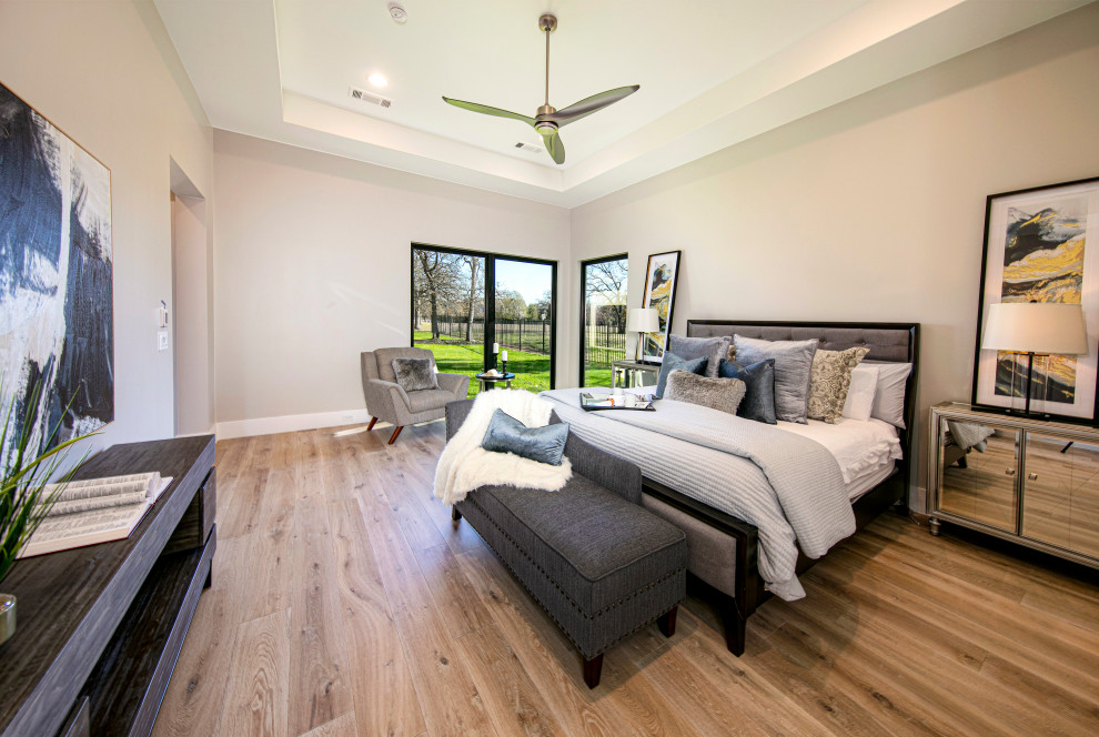 Modelo de dormitorio principal tradicional grande con paredes beige y suelo de madera clara