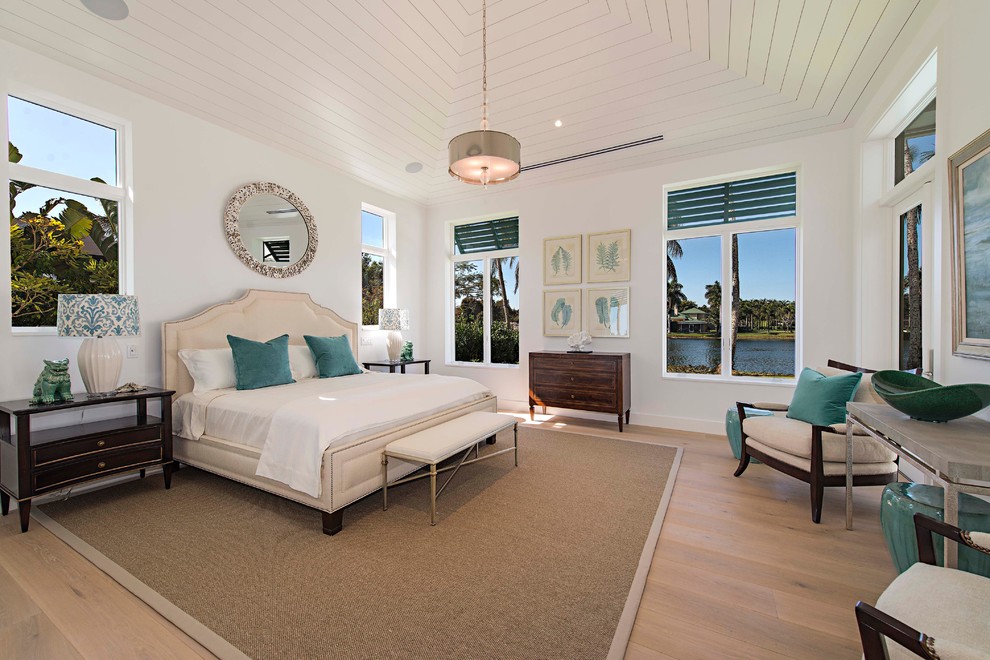 Photo of a beach style master bedroom in Miami with white walls, light hardwood flooring and feature lighting.