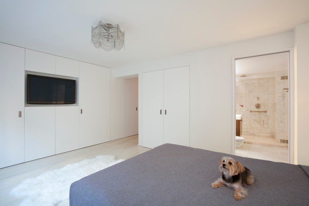Diseño de dormitorio televisión actual sin chimenea con paredes blancas y suelo de madera clara